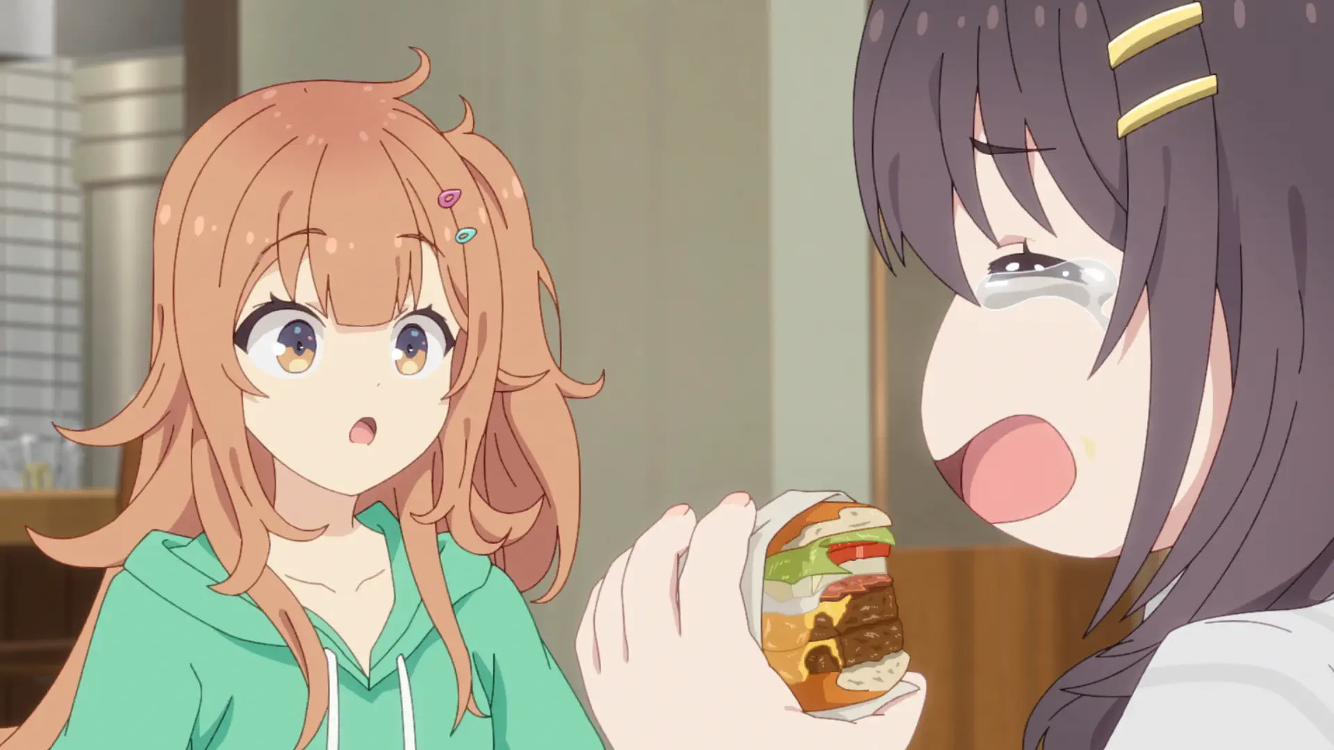 Duas personagens de anime. Da esquerda para direita: uma mulher com cabelos castanhos longos, expressão de surpresa e olhos castanhos e uma mulher de cabelos pretos longos, olhos fechados e boca aberta enquanto segura um hambúrguer.
